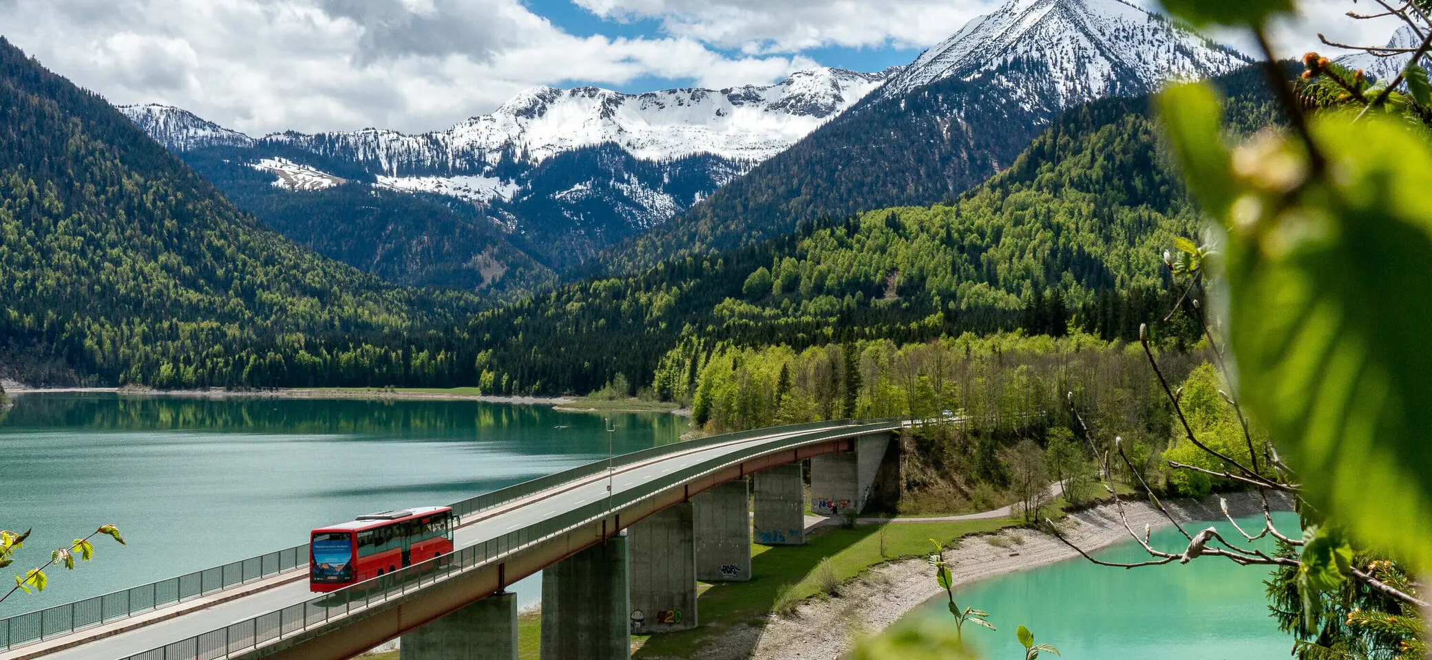 Der Bergbus des Deutschen Alpemvereins fährt über eine Brücke in die Alpen | © DAV/Tobias Hipp
